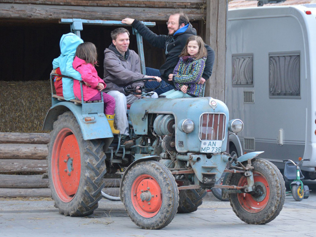 männer mit kindern fahren mit dem traktor