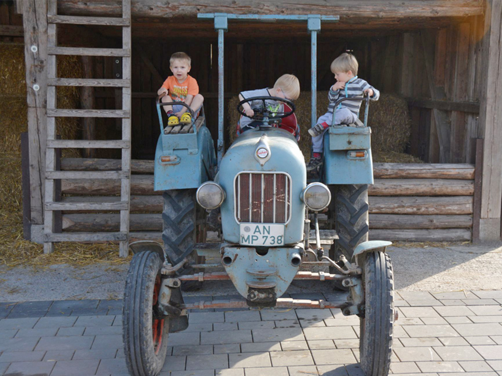 3 kleinkinder sitzen auf dem traktor