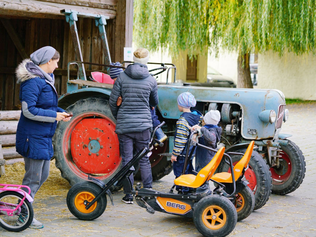 2 frauen mit kindern schauen sich den traktor an