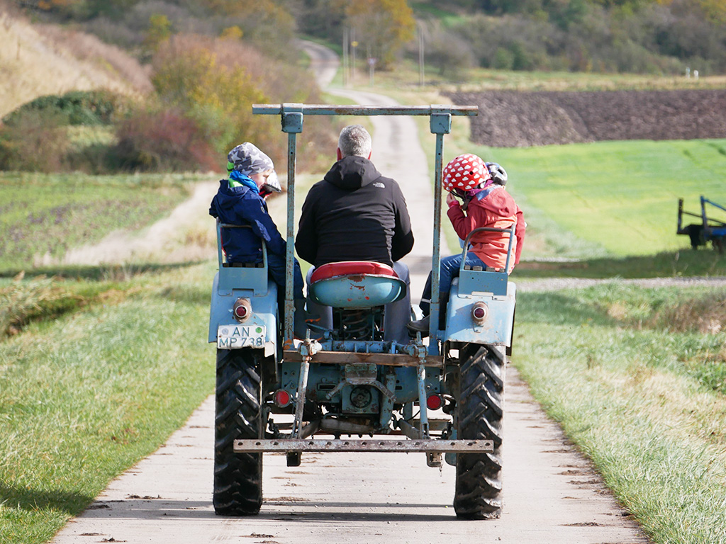 mann fährt mit kindern traktor