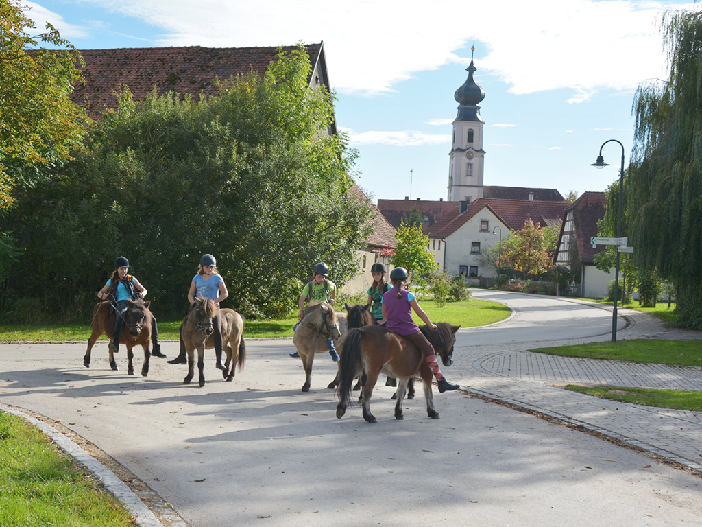 kinder reiten mit ponys durch das dorf binzwangen