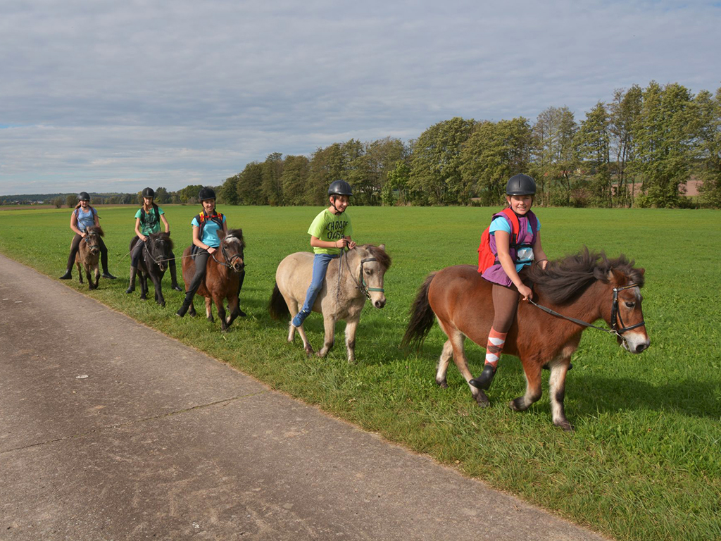 mehrere kinder reiten durch die landschaft