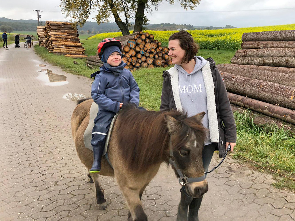 kind reitet auf pony und frau führt