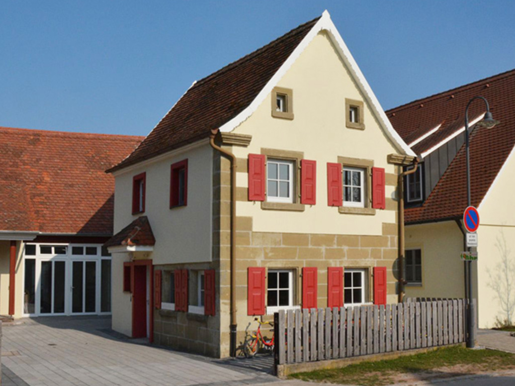 aussenansicht der alten schusterei mit roten fensterläden