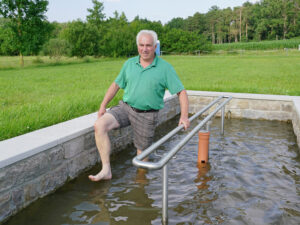 Mann läuft durch das Wassertretbecken am Badeweiher in Binzwangen