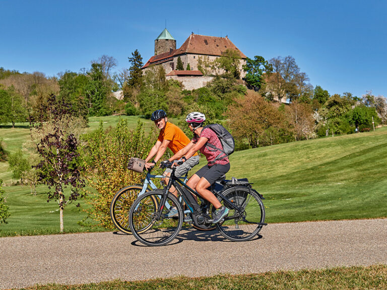 fahradfahrer im vordergrund und hintergrund die burg colmberg