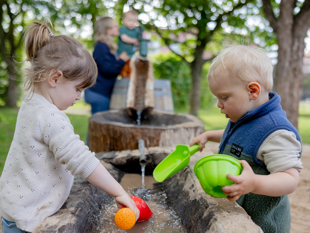 Kleinkinder spielen am Wasserspielplatz