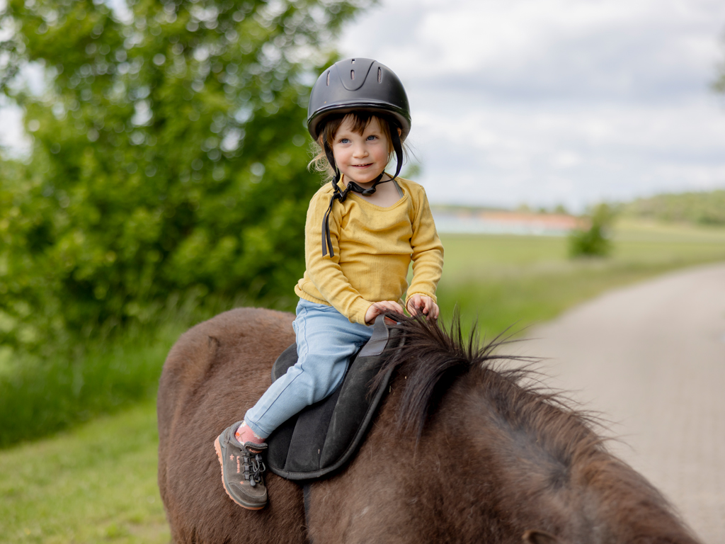 Kleinkind sitzt auf einem Pferd