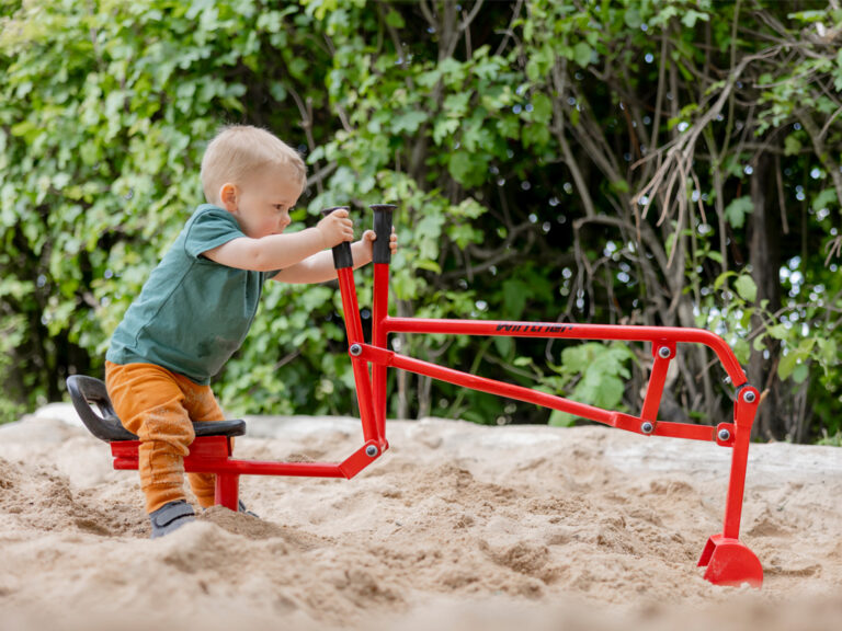 kleines Kind baggert mit dem Sandbagger Sand