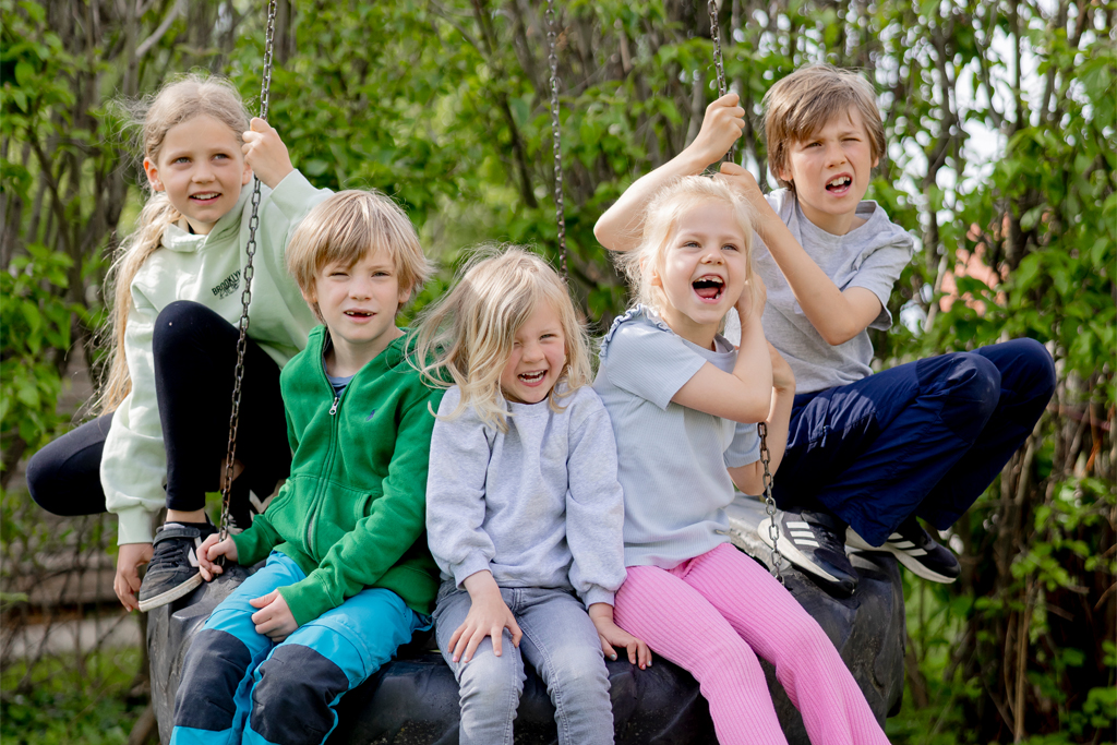 fünf Kinder sitzen auf einer Schaukel